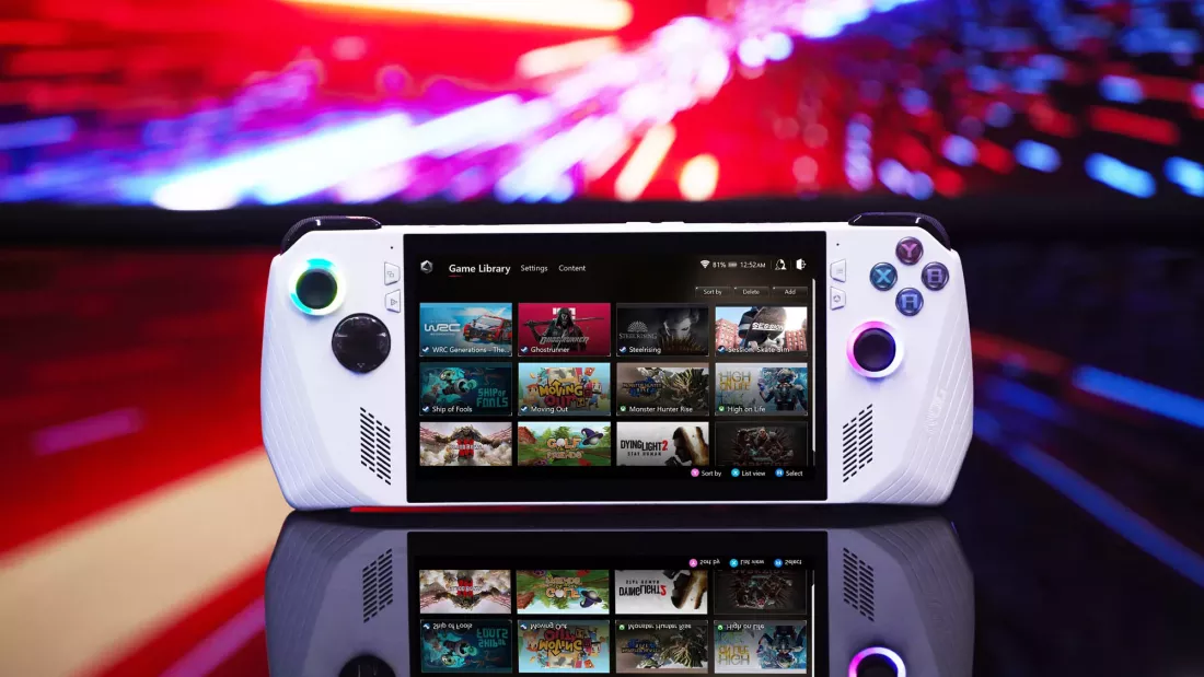 Una consola portátil de videojuegos Asus ROG Ally en primer plano, con un fondo colorido y difuminado que realza la escena. La pantalla de la consola muestra la biblioteca de juegos, destacando varios títulos organizados en filas. Los controles de la consola están iluminados, con luces en los sticks y botones que agregan un toque moderno y llamativo al diseño. El reflejo de la consola en la superficie debajo de ella también es visible, añadiendo profundidad a la composición visual.
